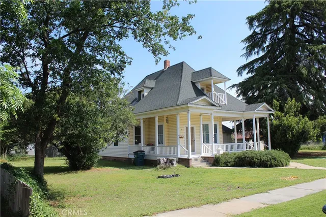 a front view of a house with a garden and trees