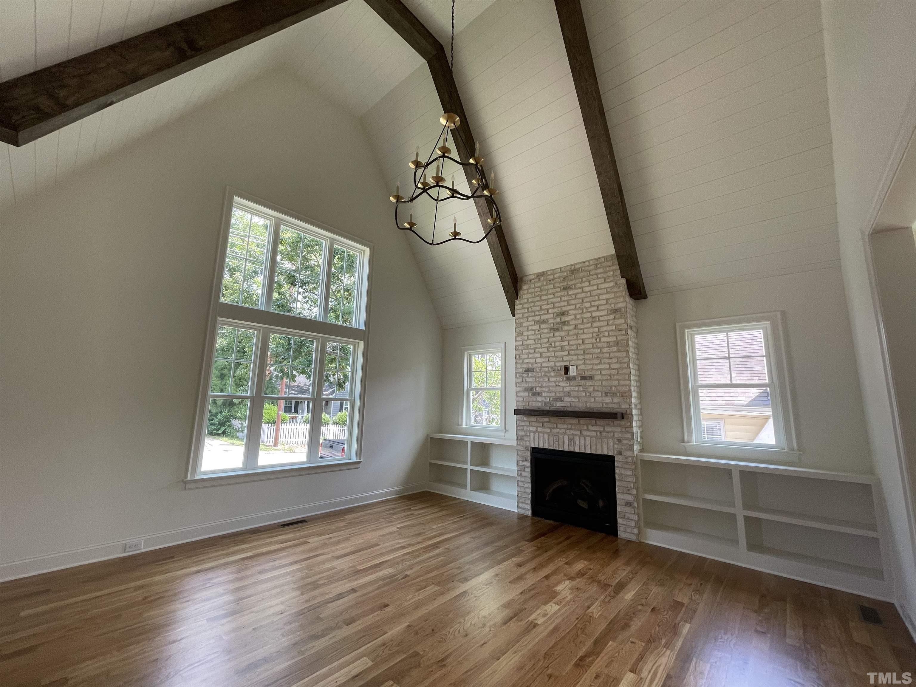 400 Pershing Road Raleigh, NC 27608 - Photo 9 of 33 an empty room with windows fireplace and wooden floor