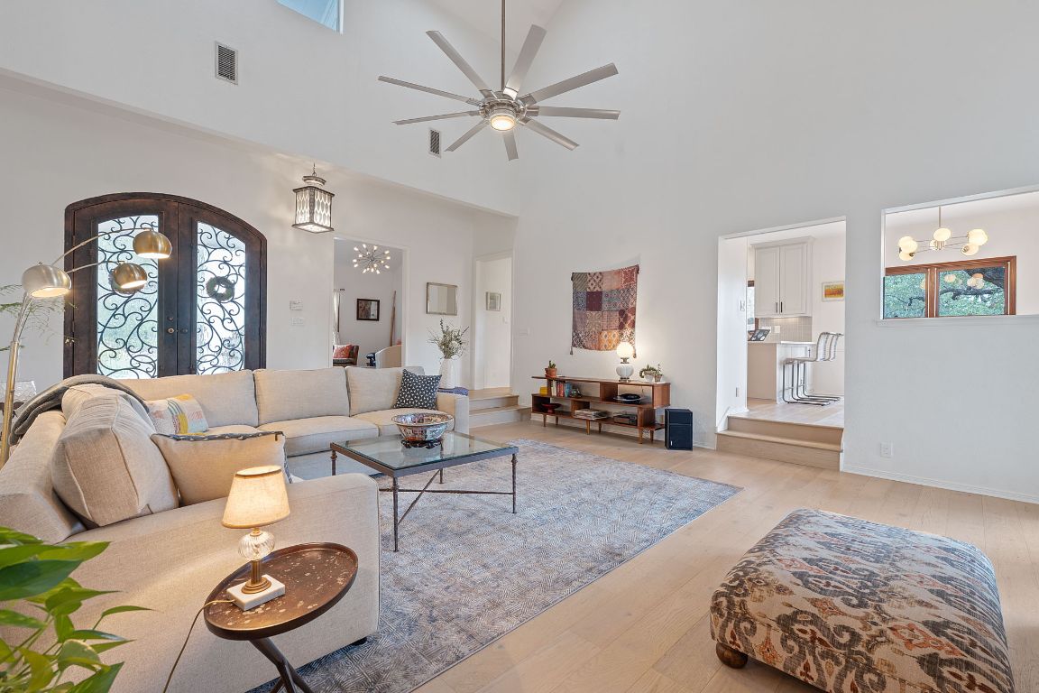 Living room with french doors, a high ceiling, light wood-style flooring, a ceiling fan, and arched walkways