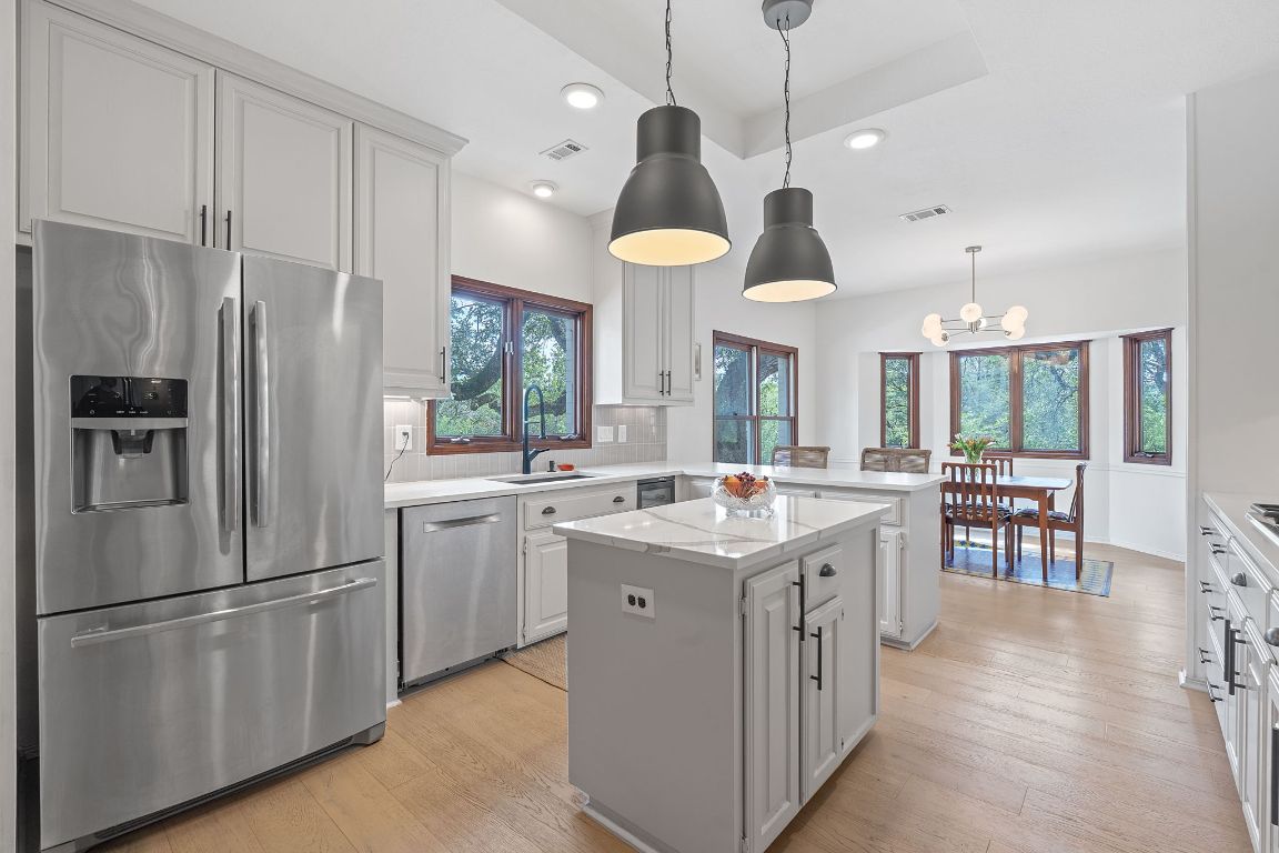 6302 Gato Path Austin, TX 78731 - Photo 11 of 37 Kitchen with stainless steel appliances, a peninsula, a kitchen island, tasteful backsplash, and light wood finished floors