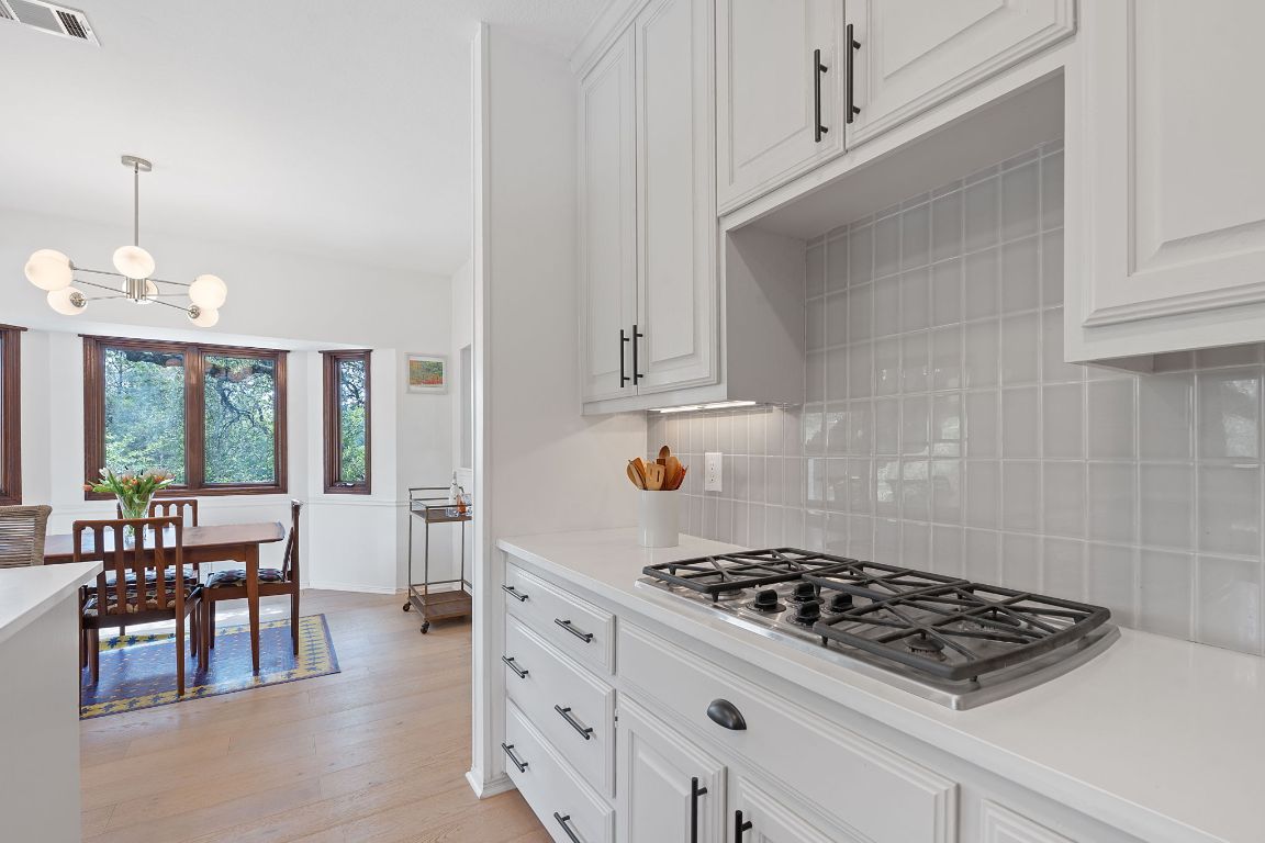 6302 Gato Path Austin, TX 78731 - Photo 13 of 37 Kitchen with stainless steel gas stovetop, decorative backsplash, light wood-style flooring, light countertops, and a chandelier