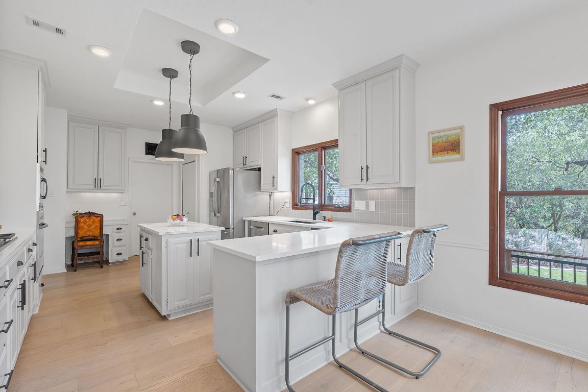 6302 Gato Path Austin, TX 78731 - Photo 7 of 37 Kitchen with stainless steel fridge with ice dispenser, light wood-type flooring, light countertops, a kitchen island, and a peninsula