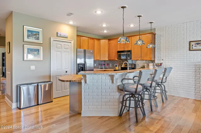 a open kitchen with stainless steel appliances granite countertop a stove top oven a dining table and chairs with wooden floor