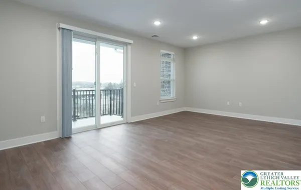 a view of an empty room with wooden floor and closet