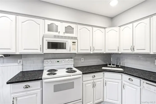 a kitchen with white cabinets and white appliances