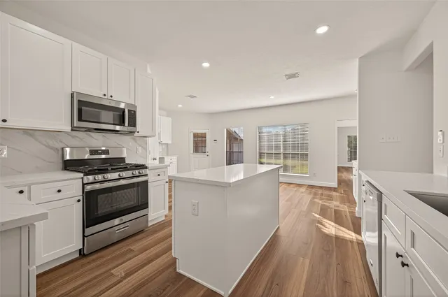 a large kitchen with stainless steel appliances granite countertop a stove and a sink