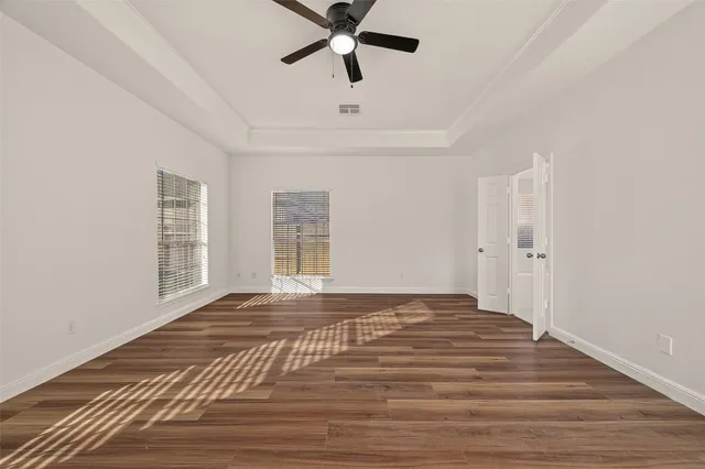 a view of empty room with wooden floor and fan