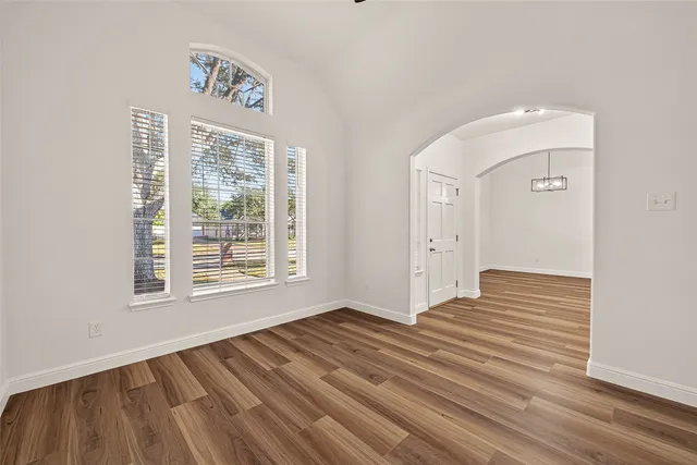 a view of an empty room with wooden floor and a window