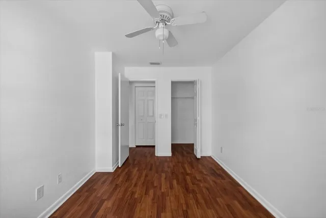 a view of a room with wooden floor a ceiling fan and a window