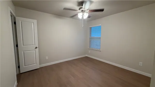 an empty room with wooden floor closet and windows