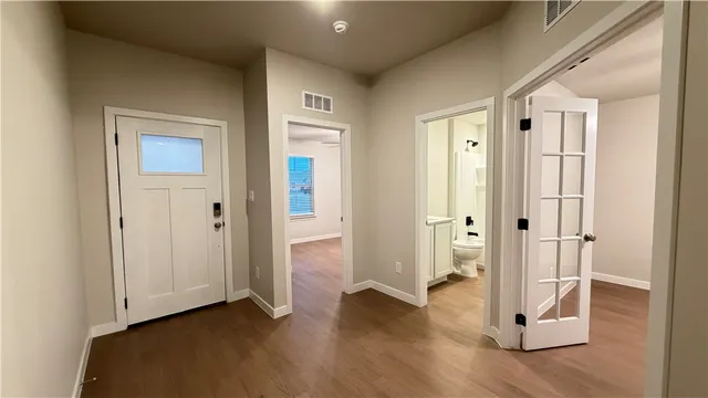 a view of a hallway with wooden floor and closet area