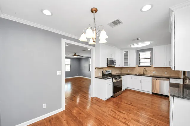 a kitchen with stainless steel appliances granite countertop a stove top oven a sink a counter space and cabinets