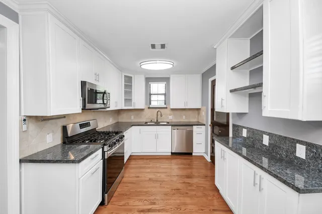a kitchen with stainless steel appliances granite countertop a sink and a stove