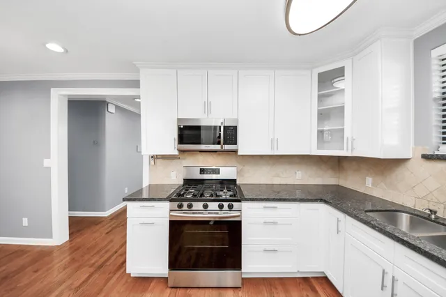 a kitchen with granite countertop a stove a sink and a microwave