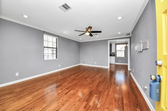 a view of empty room with wooden floor and fan
