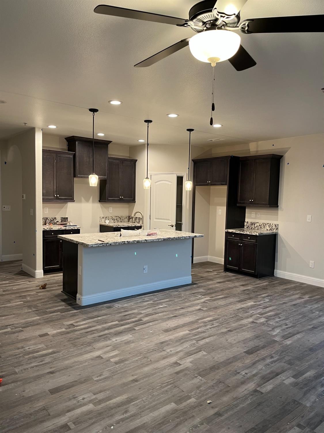 1189 Emerald Way Kerman, CA 93630 - Photo 2 of 3 a large kitchen with stainless steel appliances a large counter top a stove and a wooden floors