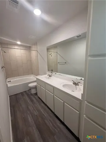 a bathroom with a double vanity sink a toilet and mirror