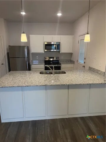 a kitchen with stainless steel appliances granite countertop a sink a stove counter space and cabinets