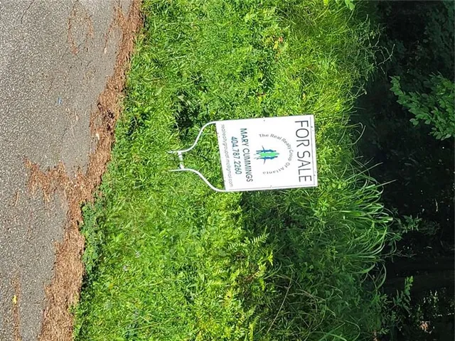 a sign that is sitting in the grass next to a road