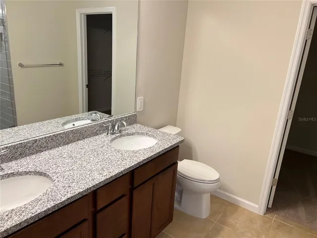 a bathroom with a granite countertop sink and a toilet