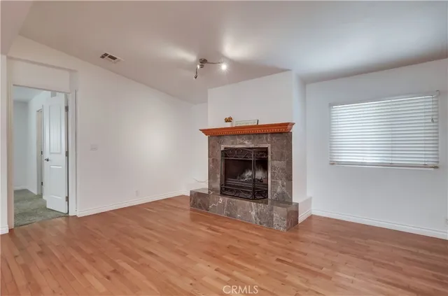 a view of an empty room with wooden floor and a chandelier