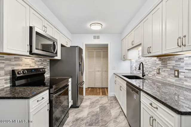 a kitchen with granite countertop a sink stove and refrigerator