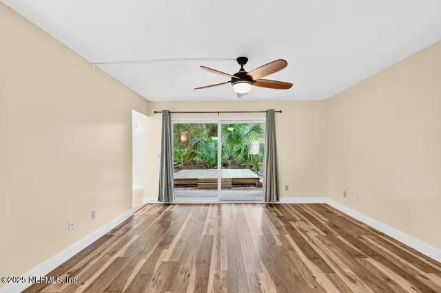 a view of empty room with wooden floor and fan