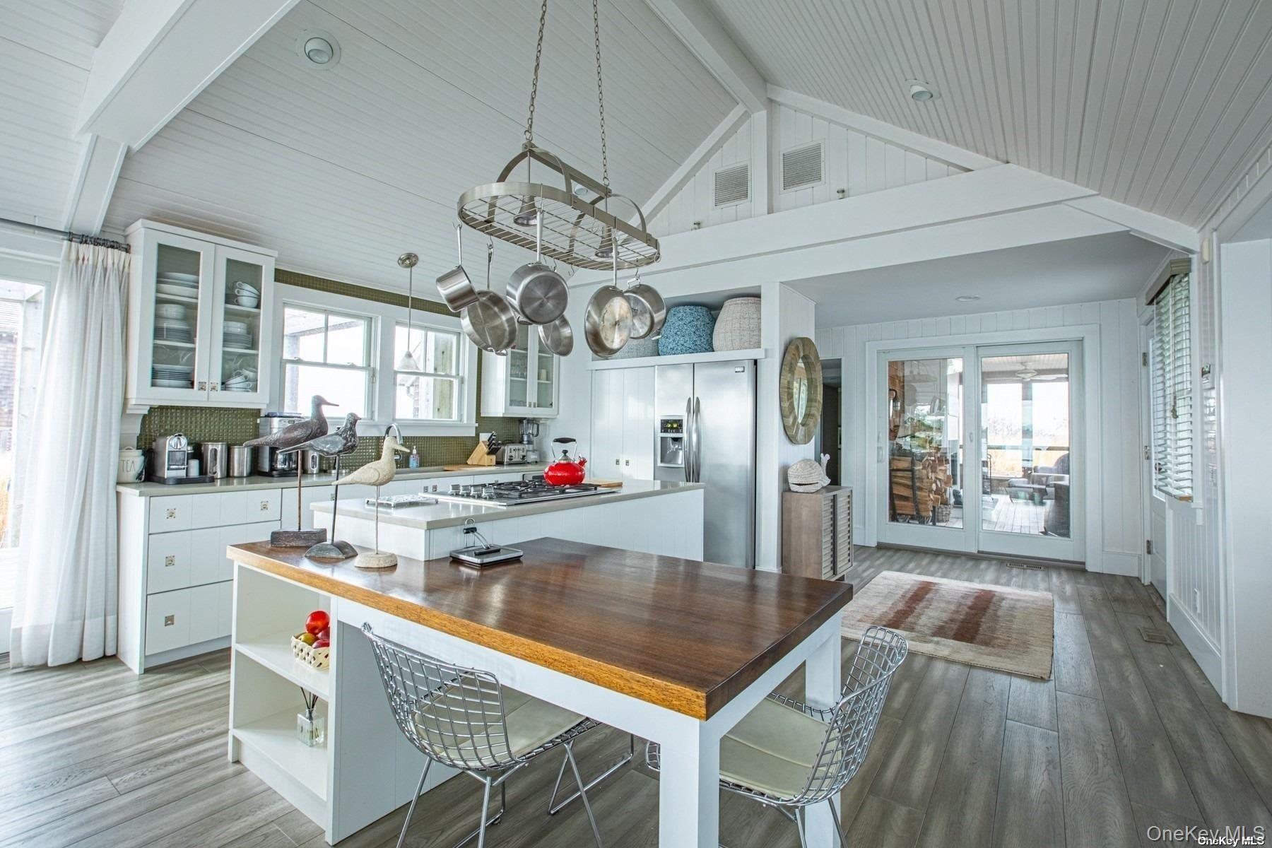11 Captree Island Babylon, NY 11702 - Photo 11 of 31 a kitchen with stainless steel appliances granite countertop a kitchen island a stove a refrigerator a sink dishwasher a dining table and chairs with wooden floor