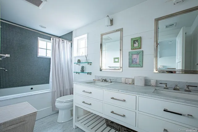 a bathroom with a double vanity sink toilet mirror and bathtub