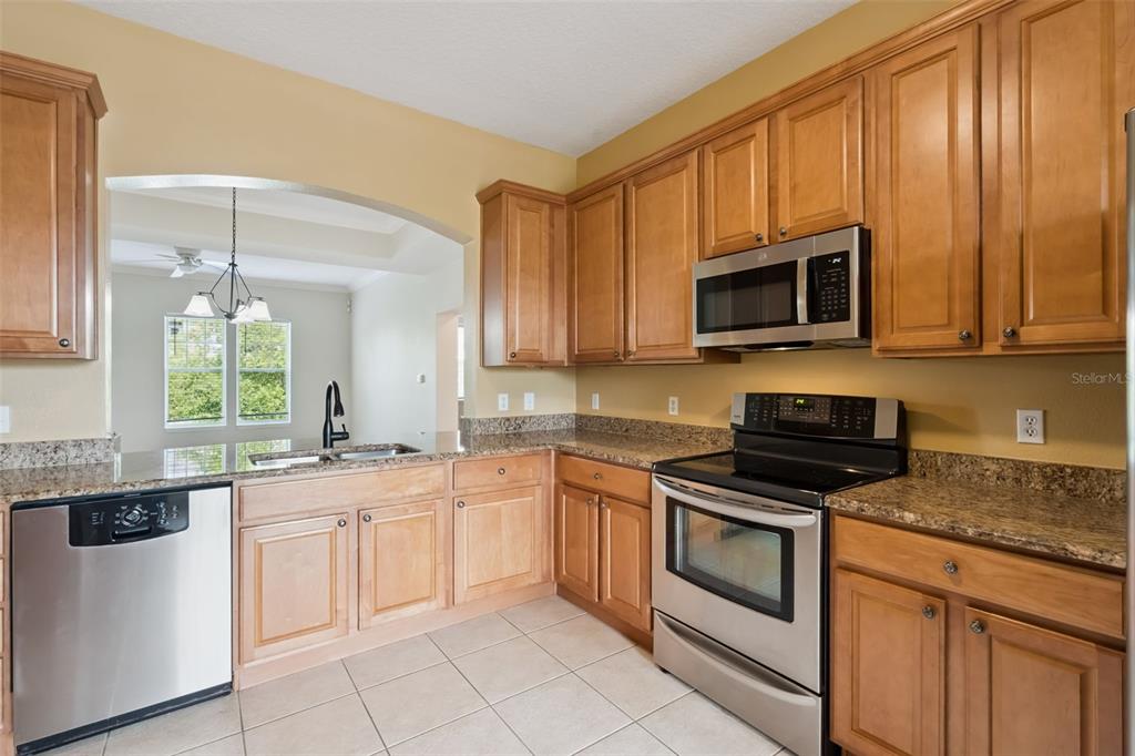 1400 Celebration Avenue, Unit 305 Celebration, FL 34747 - Photo 5 of 38 a kitchen with granite countertop white cabinets stainless steel appliances and a sink