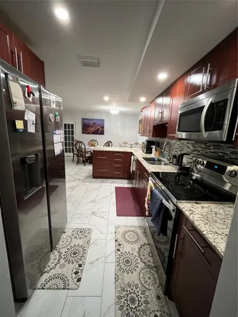 a kitchen with stainless steel appliances kitchen island granite countertop a stove a sink dishwasher and a microwave with wooden floor