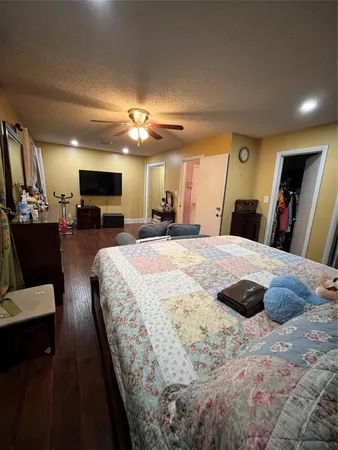 a large bedroom with a large bed a flat tv screen and dresser