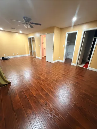 a view of an empty room with window and wooden floor