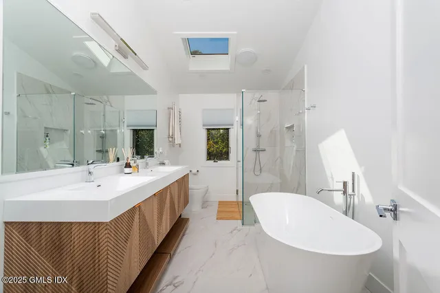 a bathroom with a double vanity sink mirror and bathtub