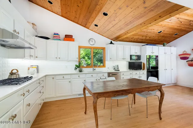 a kitchen with stainless steel appliances kitchen island granite countertop a table chairs sink and cabinets