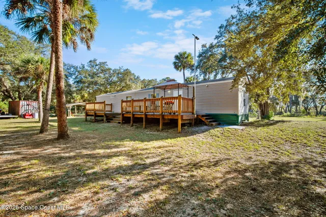 a view of a house with backyard and trees
