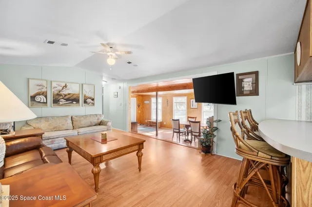 a living room with furniture kitchen view and a wooden floor