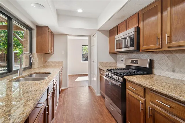 a kitchen with stainless steel appliances granite countertop a stove a sink and a refrigerator