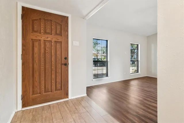 an empty room with wooden floor closet and windows