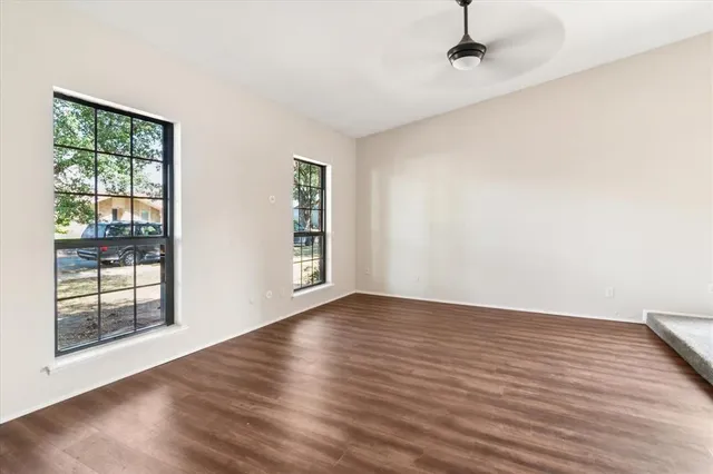 an empty room with wooden floor and windows