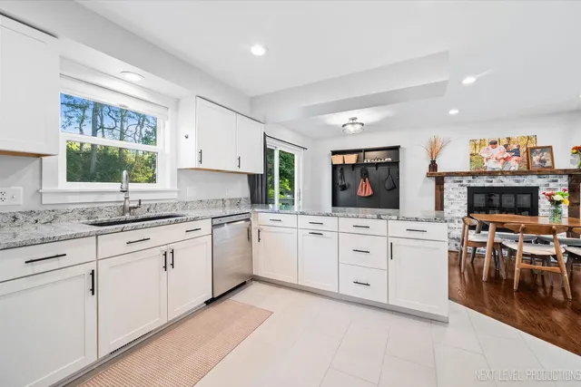 a kitchen with granite countertop white cabinets a sink a window and stainless steel appliances