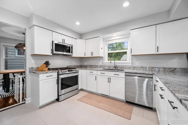 a kitchen with granite countertop white cabinets a sink a window and stainless steel appliances