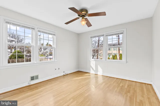 an empty room with wooden floor fan and windows