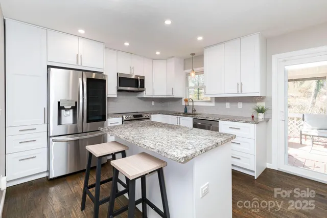 a kitchen with a refrigerator a stove a sink and white cabinets with wooden floor