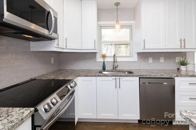 a kitchen with granite countertop a sink a stove and cabinets