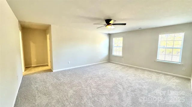 an empty room with windows and ceiling fan
