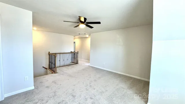an empty room with a ceiling fan and carpet