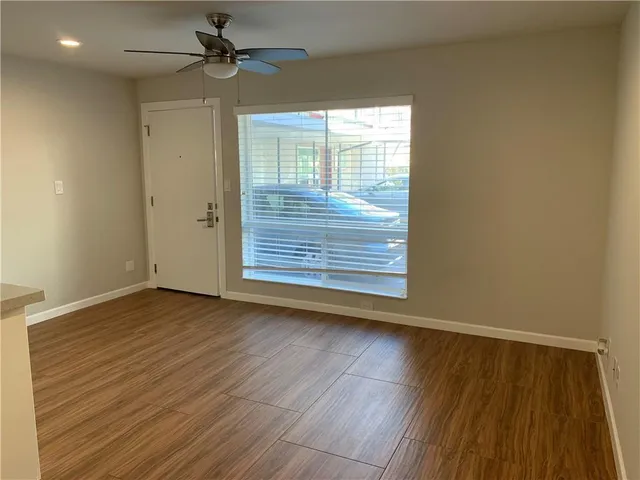 an empty room with wooden floor chandelier fan and windows