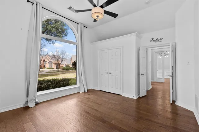 an empty room with wooden floor fan and windows