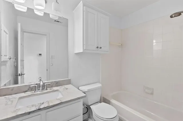 a bathroom with a granite countertop sink toilet and shower